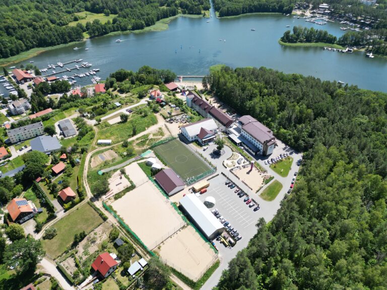 Widok z lotu ptaka na budynki noclegowe, boiska i teren Gwarka nad jeziorem Tajty